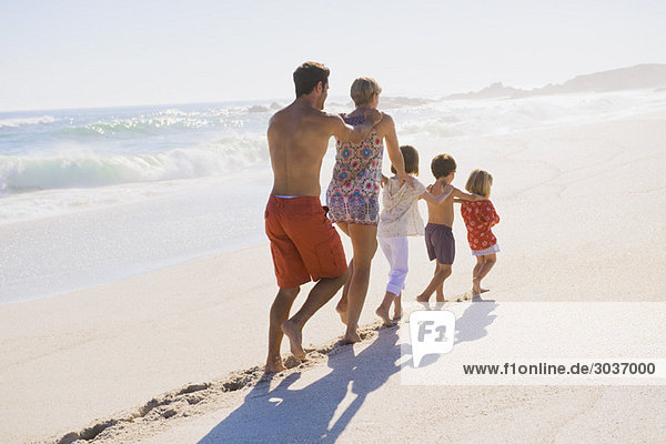 Family walking on the beach in train formation