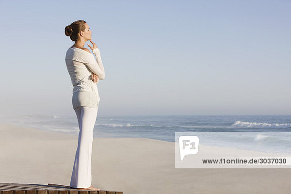 Frau steht auf einer Strandpromenade und schaut auf eine Aussicht.