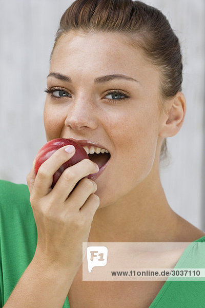 Frau isst einen Apfel und lächelt