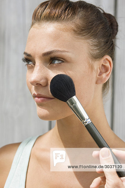 Woman applying make-up on her face