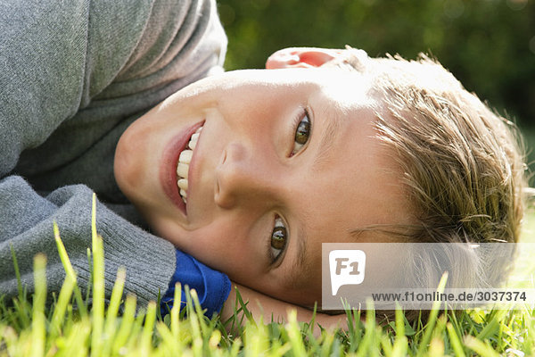 Junge auf Gras liegend und lächelnd