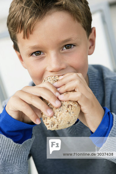 Porträt eines Jungen  der ein Brötchen isst