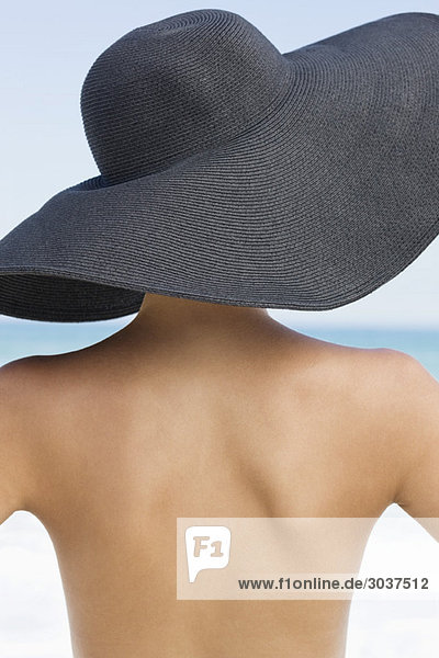 Rückansicht einer Frau mit Hut am Strand