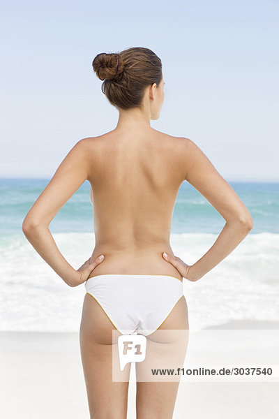 Rear view of a woman standing on the beach and looking at a view