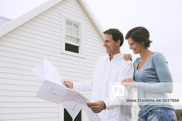 Ein Paar sieht sich einen Bauplan eines Hauses an.
