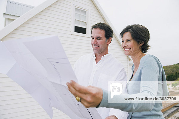 Ein Paar sieht sich einen Bauplan eines Hauses an.