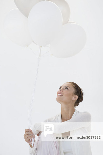 Frau hält Luftballons und lächelt