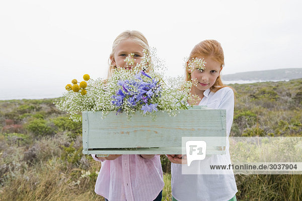 Zwei Mädchen mit einer Schachtel Blumen.