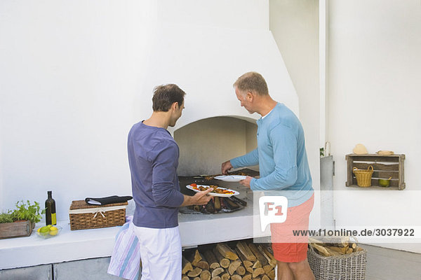 Zwei Männer kochen Kebab am Kamin