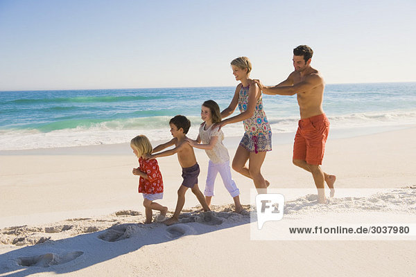Family walking on the beach in train formation