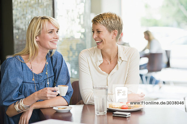 Two women sitting in a restaurant and smiling