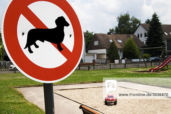 ein Hundeverbotsschild steht vor einem Kinderspielplatz