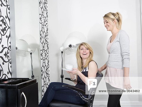 Hairdresser serving coffee to customer