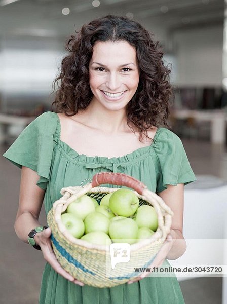 woman holding basket of apples