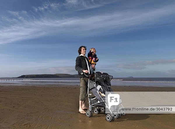 man at beach with pushchair and child