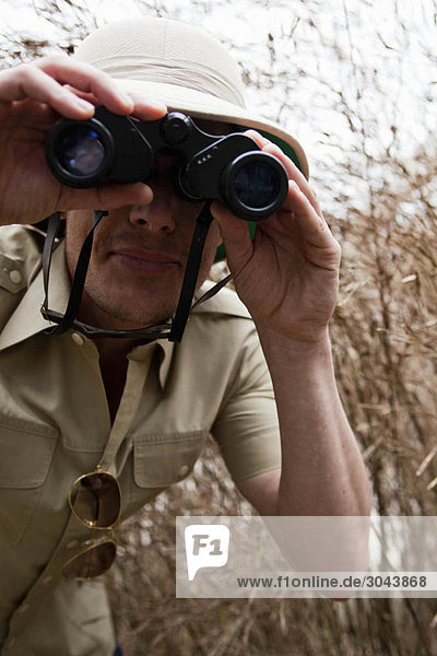 man in jungle outfit using binoculars