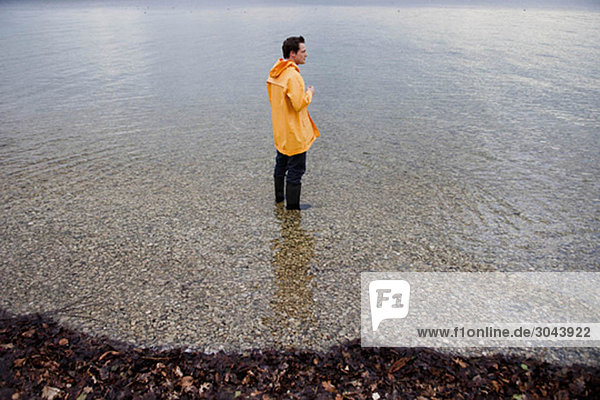 man in raincoat in shallow water