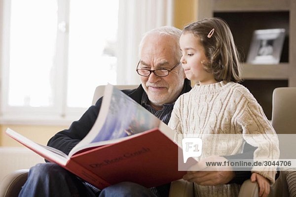 old man reading book to young girl