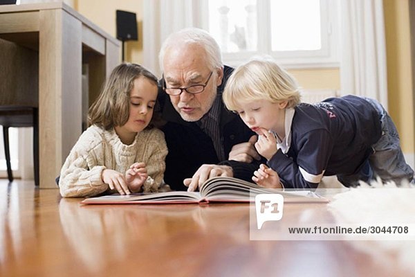 old man reading book to children