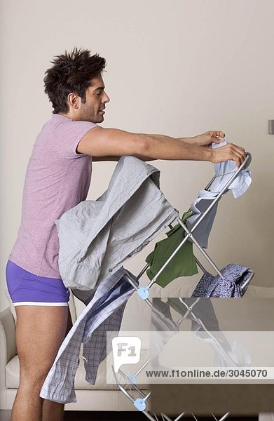 Mann hängt nasse Wäsche am Trockner auf