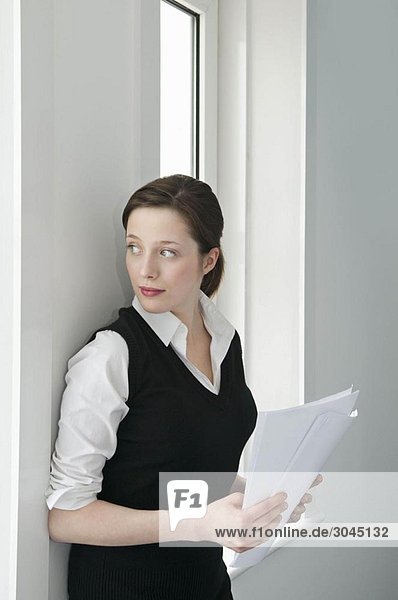 Eine Geschäftsfrau die aus dem Fenster schaut.