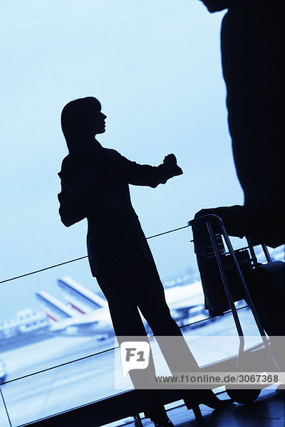 Silhouette einer Reisenden stehend mit Gepäckwagen auf dem Flughafen