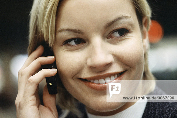 Woman phoning using cell phone smiling  glancing sideways  portrait