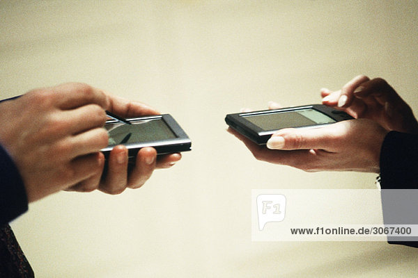 Two people exchanging information using personal digital assistants