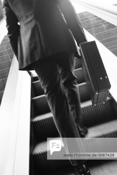 Geschäftsmann mit Aktentasche aufsteigende Rolltreppe  Rückansicht