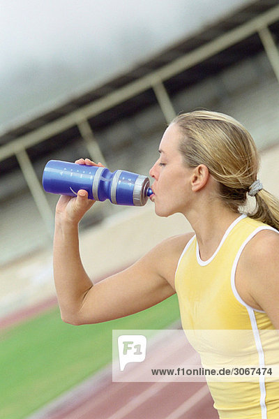 Sportlerin trinkt Wasser aus der Flasche