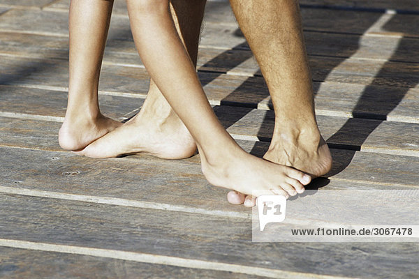 Person standing on top of another person's bare feet  cropped