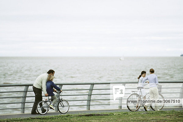 Familie reitet gemeinsam im Seepark  Vater hilft dem Sohn  das Fahren zu lernen