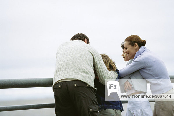 Familie zusammen am Meer  Eltern umarmen Kinder