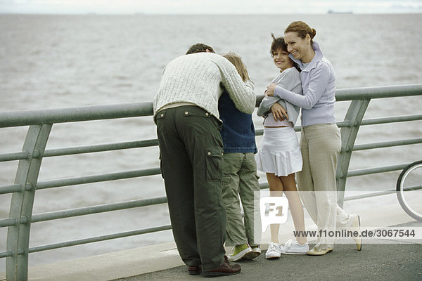 Familie zusammen am Meer  Eltern umarmen Kinder  Vater tröstender Sohn