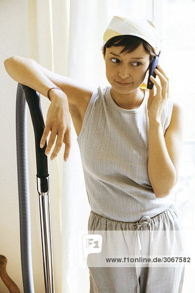 Frau macht Pause von der Hausarbeit für einen Telefonanruf  schaut weg