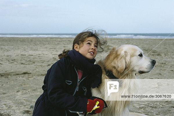 Junges Mädchen mit Hund am Strand beim Drachenfliegen