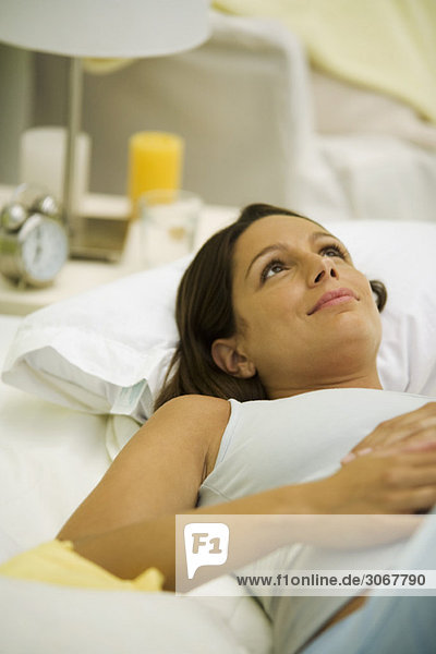 Pregnant woman lying on bed  daydreaming