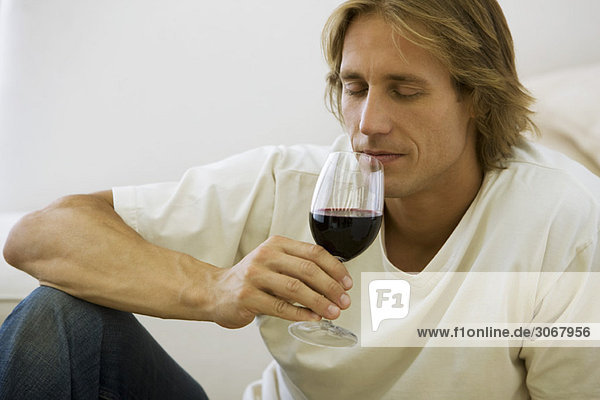 Mann genießt Bouquet von einem Glas Rotwein