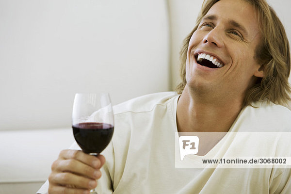 Mann  der ein Glas Rotwein hält  lacht.