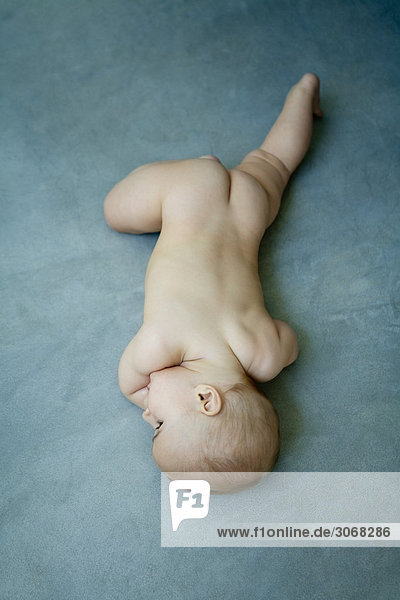 Nacktes Baby auf dem Bauch auf dem Boden liegend  volle Länge  Hochwinkelansicht
