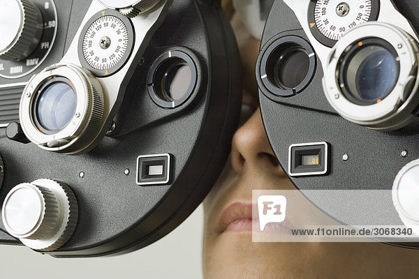 Patient schaut in den Phoropter in der Augenarztpraxis  extreme Nahaufnahme