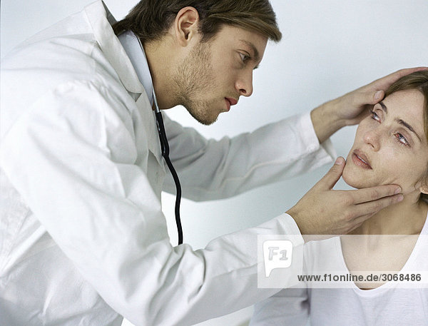 Ärztin kippt den Kopf der Patientin zurück  um ihr Auge zu untersuchen.
