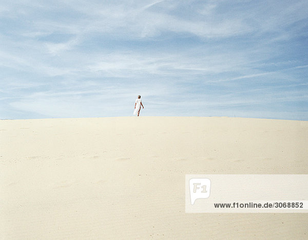 Woman standing on sand  in distance