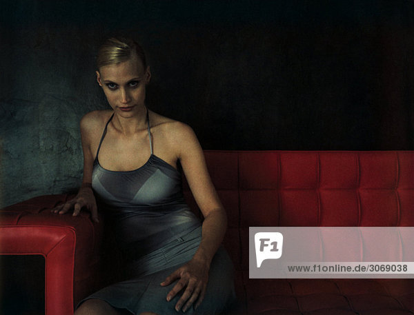 Woman sitting on red sofa  looking at the camera