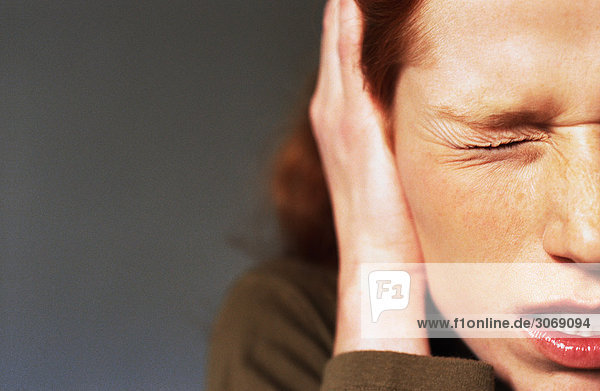 Junge Frau schielendes Auge geschlossen  Hand bedeckendes Ohr  Nahaufnahme