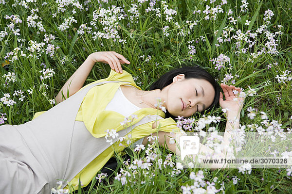 Junge Frau im Blumenfeld liegend