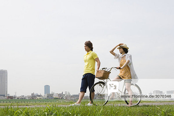 Young man walking and young woman on bicycle