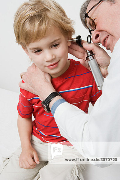 Arzt schaut in das Ohr des Jungen