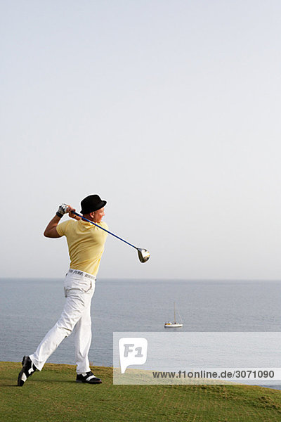 A man playing golf by the sea Gran Canaria Spain.