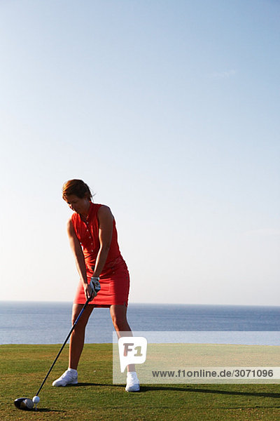A woman playing golf by the sea Gran Canaria Spain.